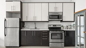 Una cocina moderna con electrodomésticos de acero inoxidable, armarios blancos y encimera negra.