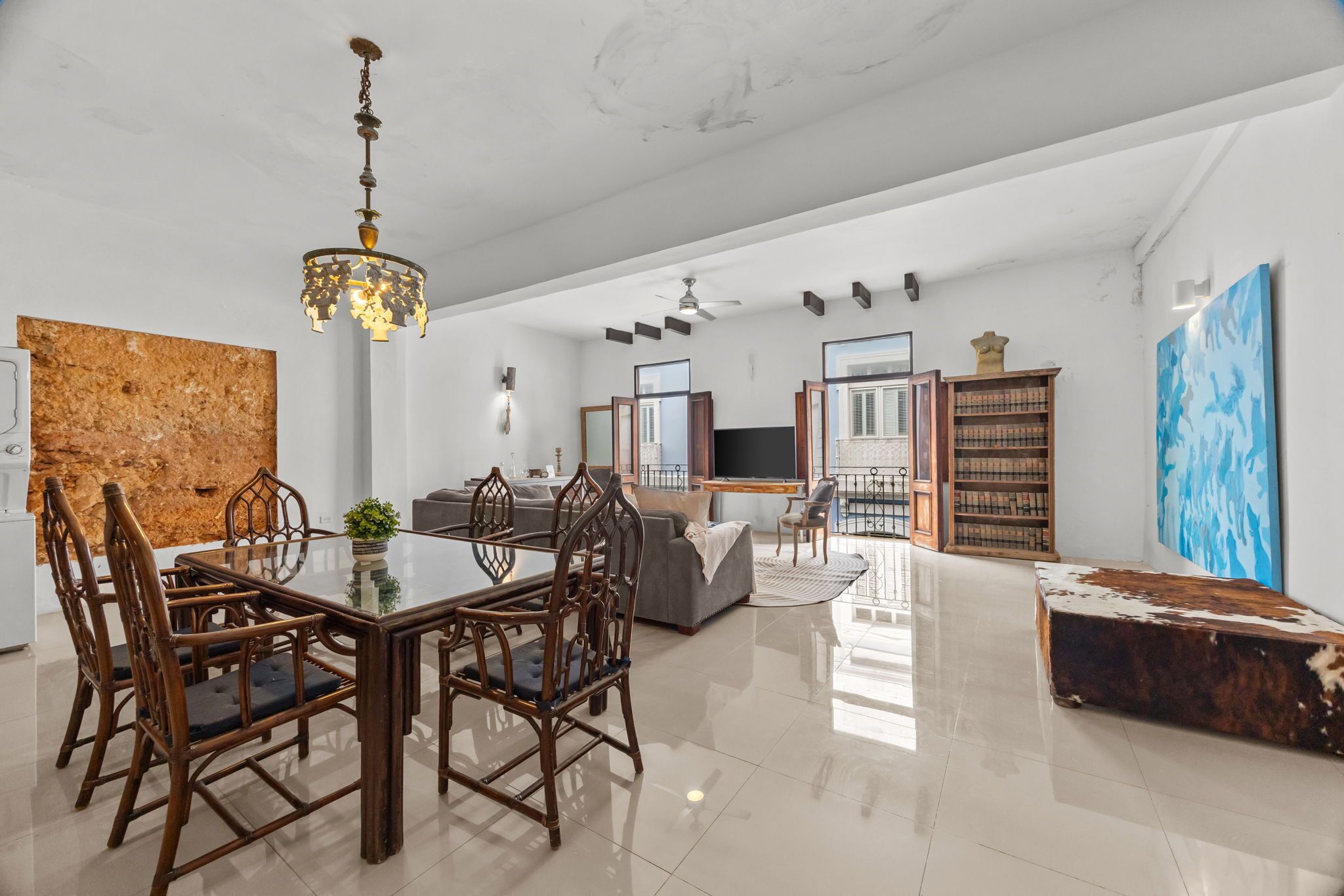A spacious living area with a dining table, chairs, a sofa, and a television.
