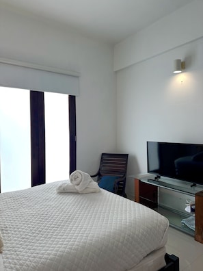 A hotel room with a bed, a television, a chair, and a window.