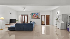 Amplia sala de estar con un sofá azul, un televisor de pantalla plana y un ventilador de techo.
