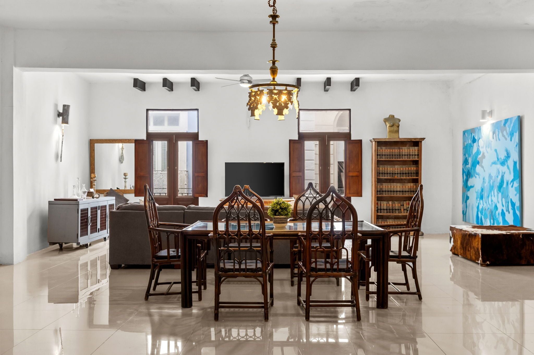A dining area with a chandelier, a television, and a bookshelf.