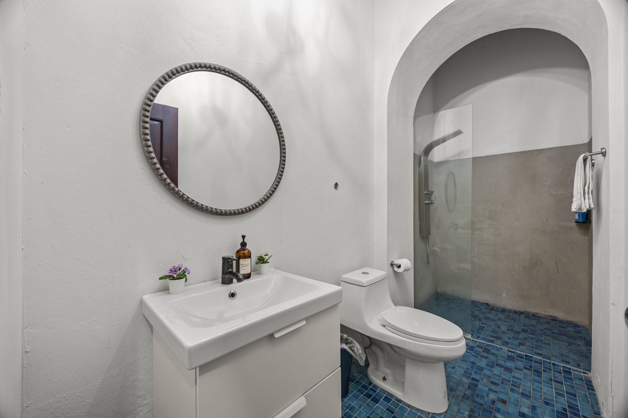 Une salle de bain avec un lavabo blanc, des toilettes et un espace douche.