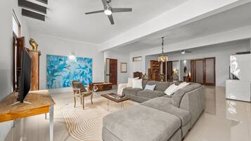 A spacious living room with a large grey sectional sofa, a wooden coffee table, and a modern ceiling fan.