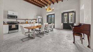 Una cocina amplia con electrodomésticos modernos, un comedor con mesa y sillas de madera, y un piano en la esquina.