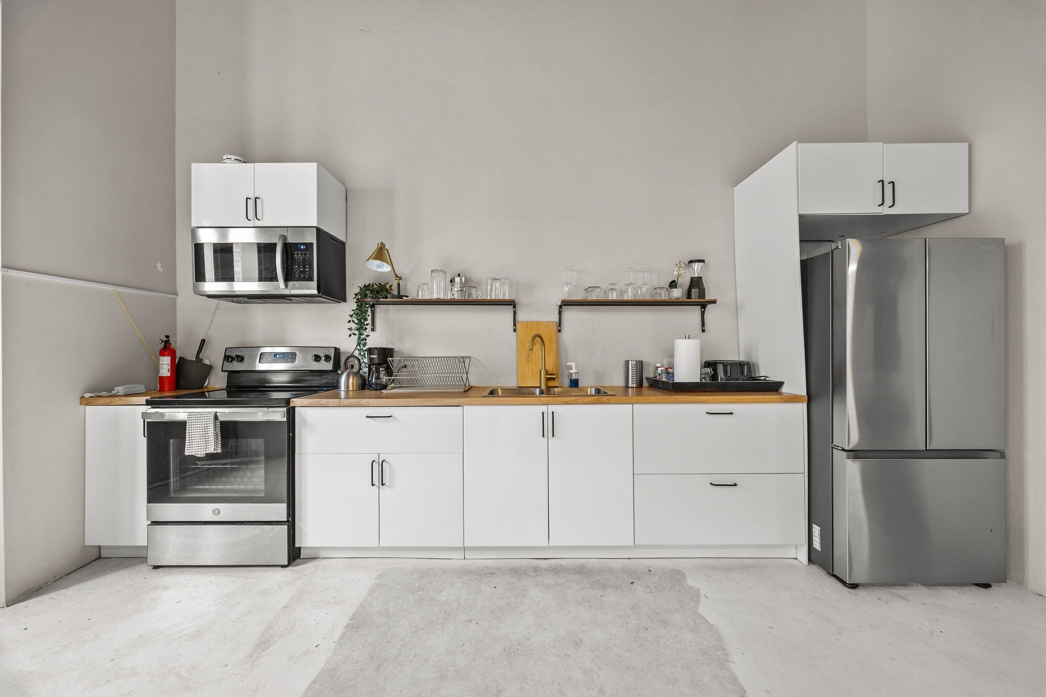 A modern kitchen with white cabinetry, stainless steel appliances, and a wooden countertop.