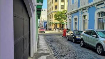 Una estrecha calle adoquinada flanqueada por edificios, incluyendo un edificio de esquina amarillo y uno azul con detalles blancos.