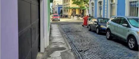 Una estrecha calle adoquinada flanqueada por edificios, incluyendo un edificio de esquina amarillo y uno azul con detalles blancos.