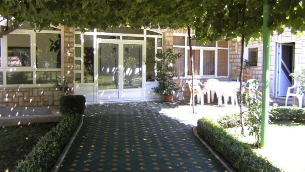 A covered outdoor area with a patterned floor, potted plants, and outdoor furniture.