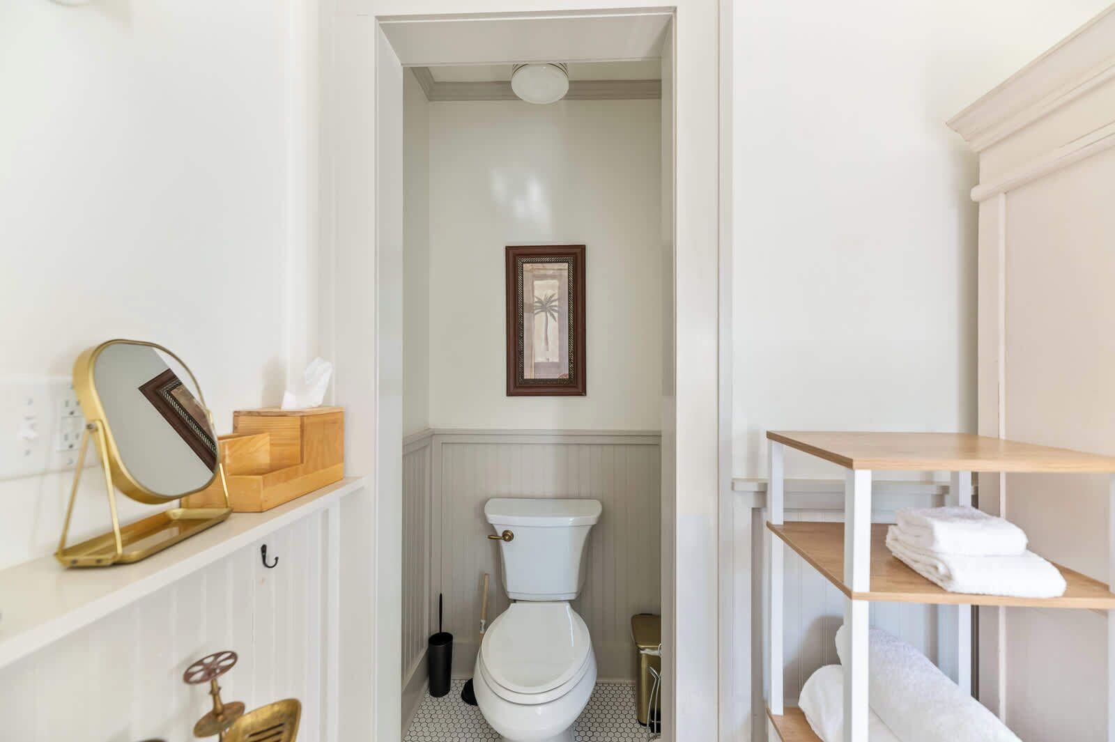 Une salle de bain comprenant des toilettes, un lavabo, un miroir et une étagère avec des serviettes.