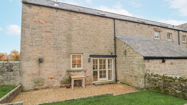 A stone building with a small garden area, a window, and a door. - Watermill Cottage (Chathill)