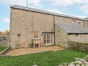 A stone building with a small garden area, a window, and a door. - Watermill Cottage (Chathill)