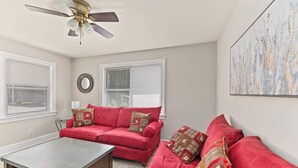 A living room with a red sofa set, a coffee table, and a ceiling fan. - Stylish North Charleston Stay | Comfort + Convenience (North Charleston)