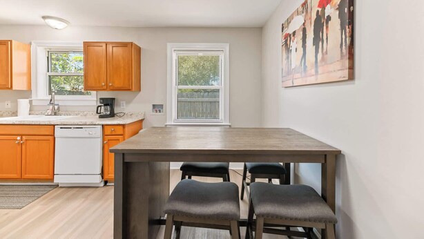 A modern kitchen with wooden cabinets, a dishwasher, a coffee maker, and a window with blinds. - Stylish North Charleston Stay | Comfort + Convenience (North Charleston)
