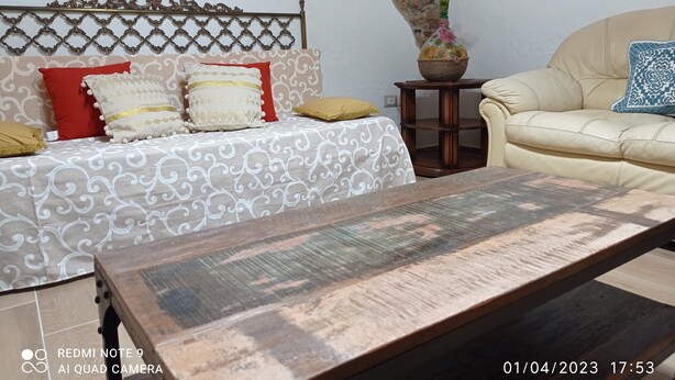 A living room with a patterned sofa, a wooden coffee table, and a small side table with a vase.