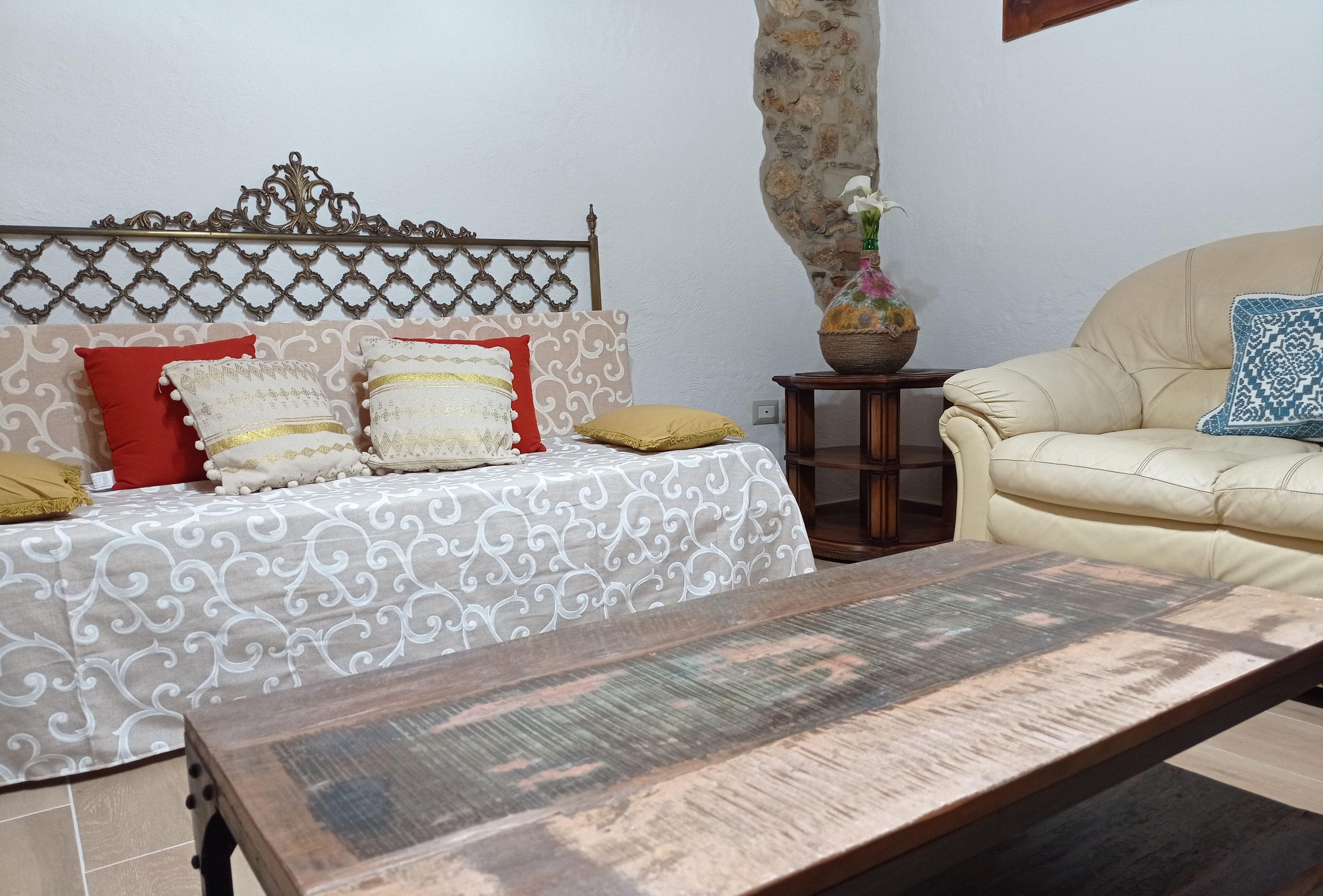 A living room with a patterned sofa, a wooden coffee table, and a small side table with a vase.