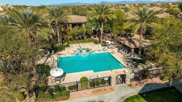 A rectangular swimming pool with a hot tub, surrounded by palm trees and lounge chairs, set in a landscaped area with a view of distant mountains. - Upscale Condo Pool View Near High Street and Mayo Clinic (Phoenix)