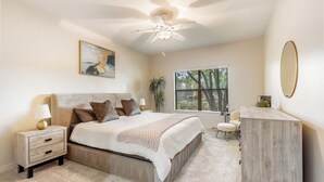 A bedroom with a bed, nightstands, a dresser, a ceiling fan, a window, and a painting on the wall. - Upscale Condo Pool View Near High Street and Mayo Clinic (Phoenix)