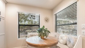A corner room with a round wooden table, white cushioned seating, and a potted plant. - Upscale Condo Pool View Near High Street and Mayo Clinic (Phoenix)