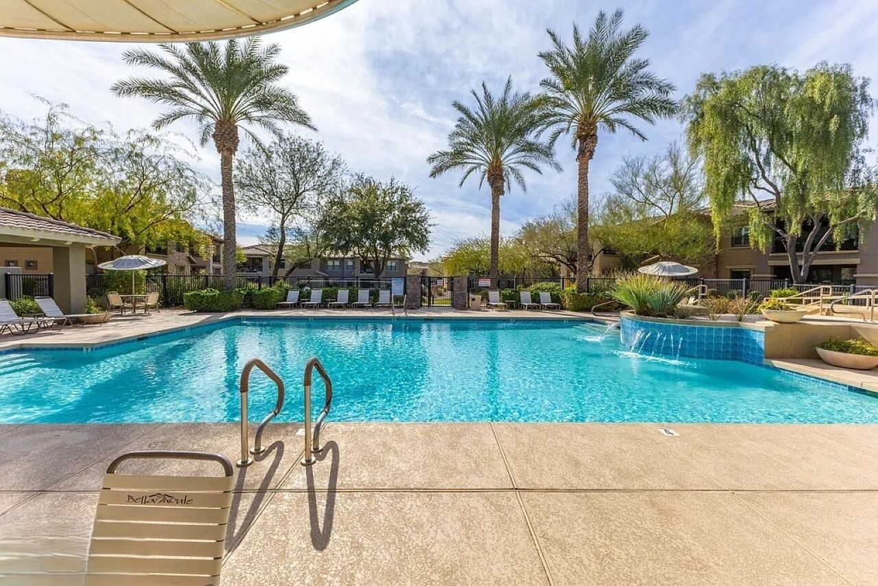 A pool area with lounge chairs and palm trees.