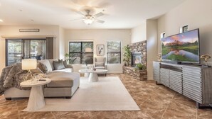 A modern living room with a sofa, coffee table, TV, and fireplace. - Upscale Condo Pool View Near High Street and Mayo Clinic (Phoenix)