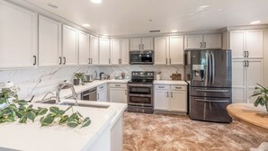 A modern kitchen with white cabinets, stainless steel appliances, and a marble backsplash. - Upscale Condo Pool View Near High Street and Mayo Clinic (Phoenix)