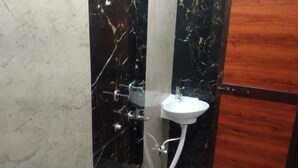 A bathroom with a marble wall, a wooden door, and a white sink. - MANGAL DHAM DEOGHAR  (Deoghar)