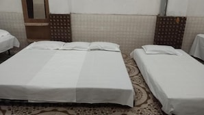 A room with two beds, each with white linens, a patterned floor, and a mirror on the wall. - MANGAL DHAM DEOGHAR  (Deoghar)