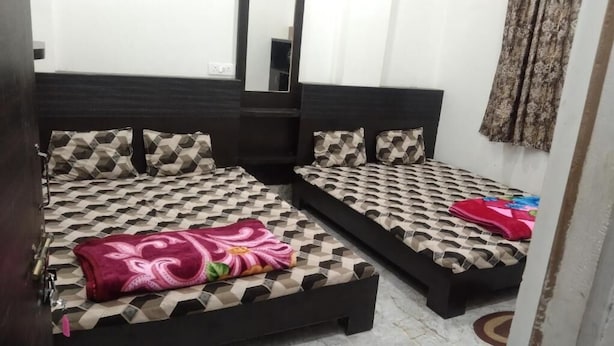 A hotel room with two beds, each with patterned bedding and pillows. - MANGAL DHAM DEOGHAR  (Deoghar)