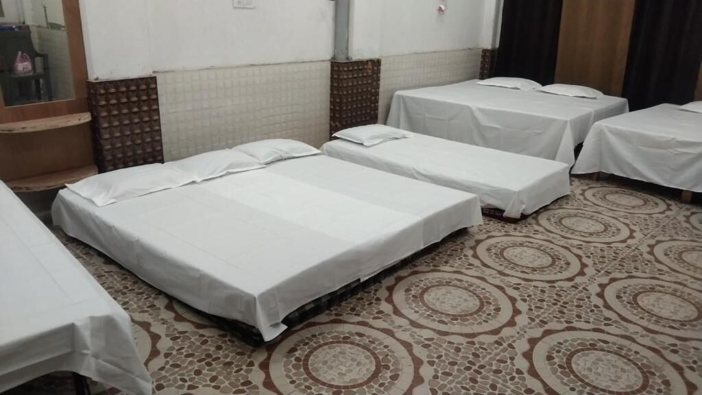 Une chambre d’hôtel avec quatre lits simples, une moquette à motifs et un mur recouvert de carreaux.