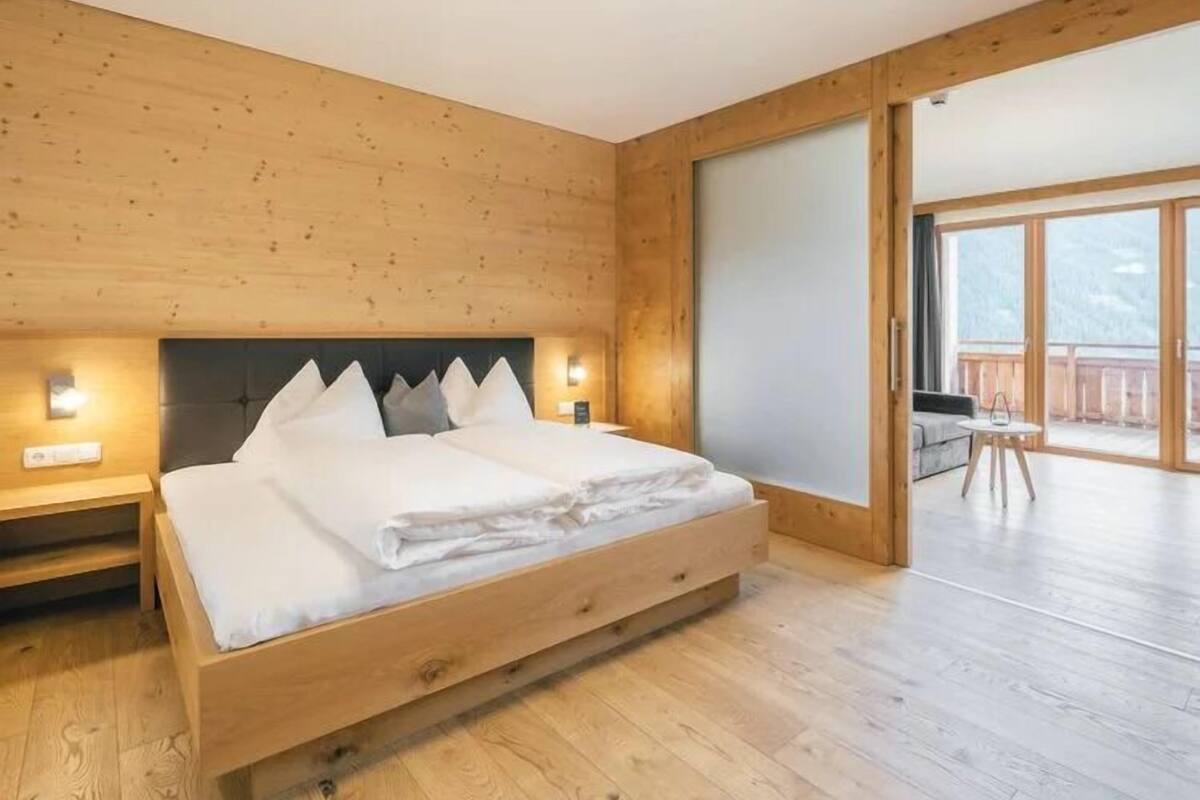 A bedroom with a wooden bed, nightstands, and a large sliding glass door leading to a balcony.