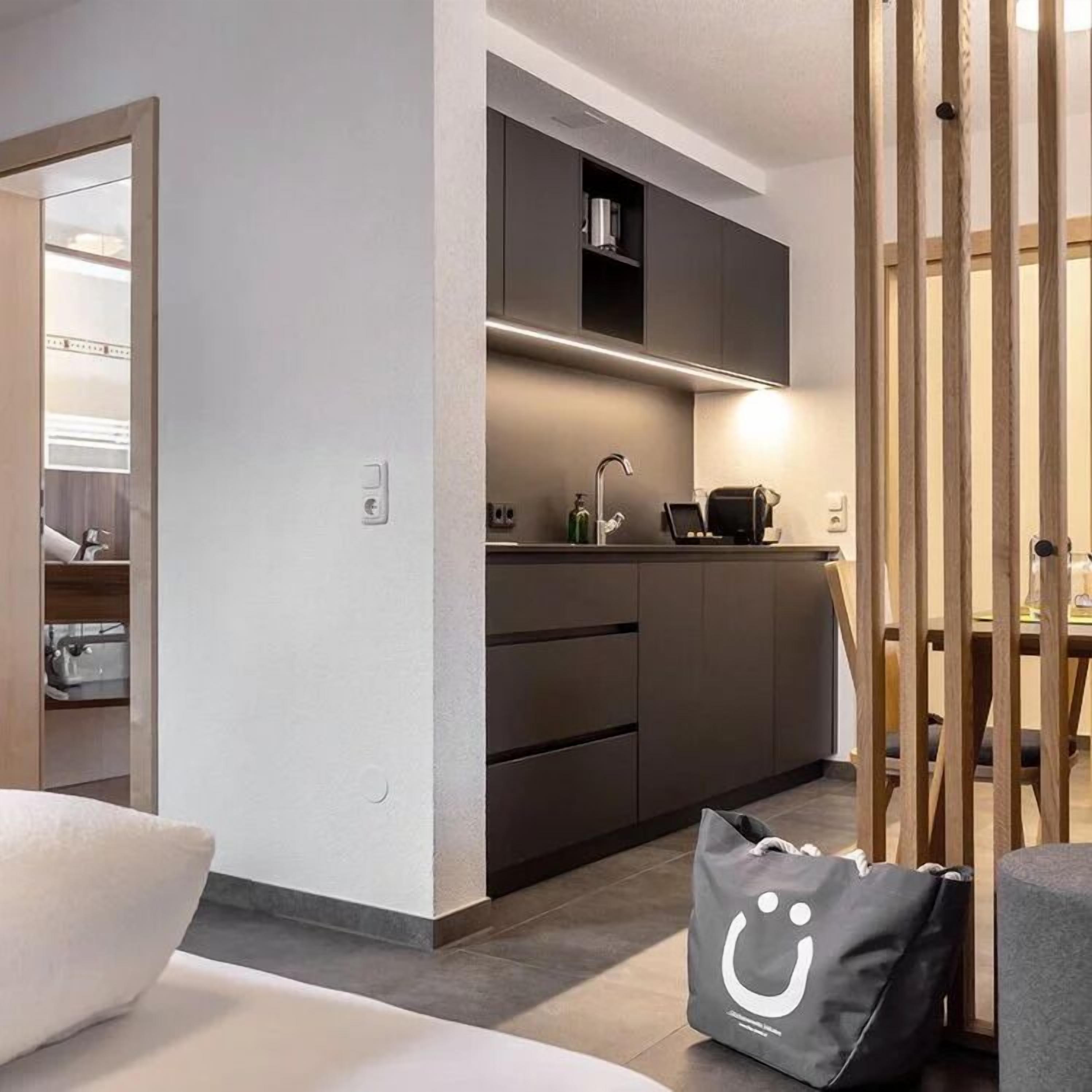 A modern kitchen with dark cabinets, a built-in oven, and a countertop with a coffee machine.
