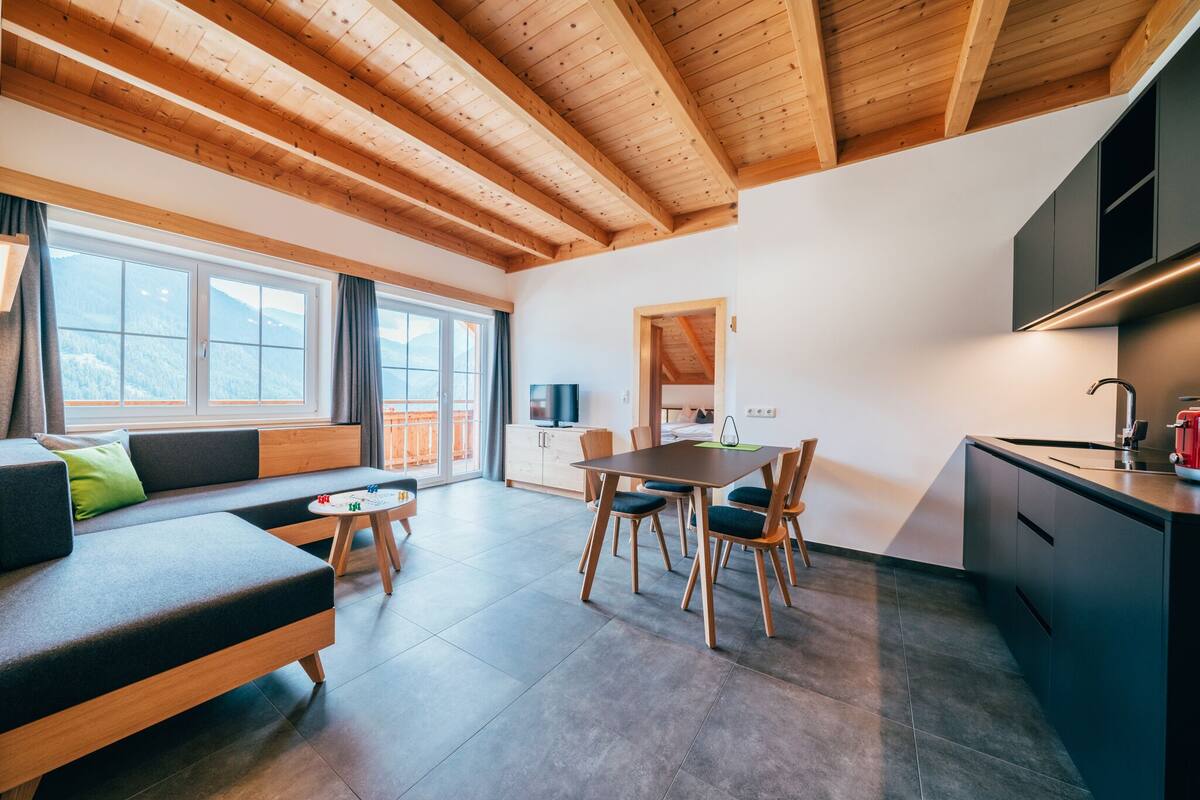 A modern interior with a wooden ceiling, a dining area, a sofa, and a kitchen.