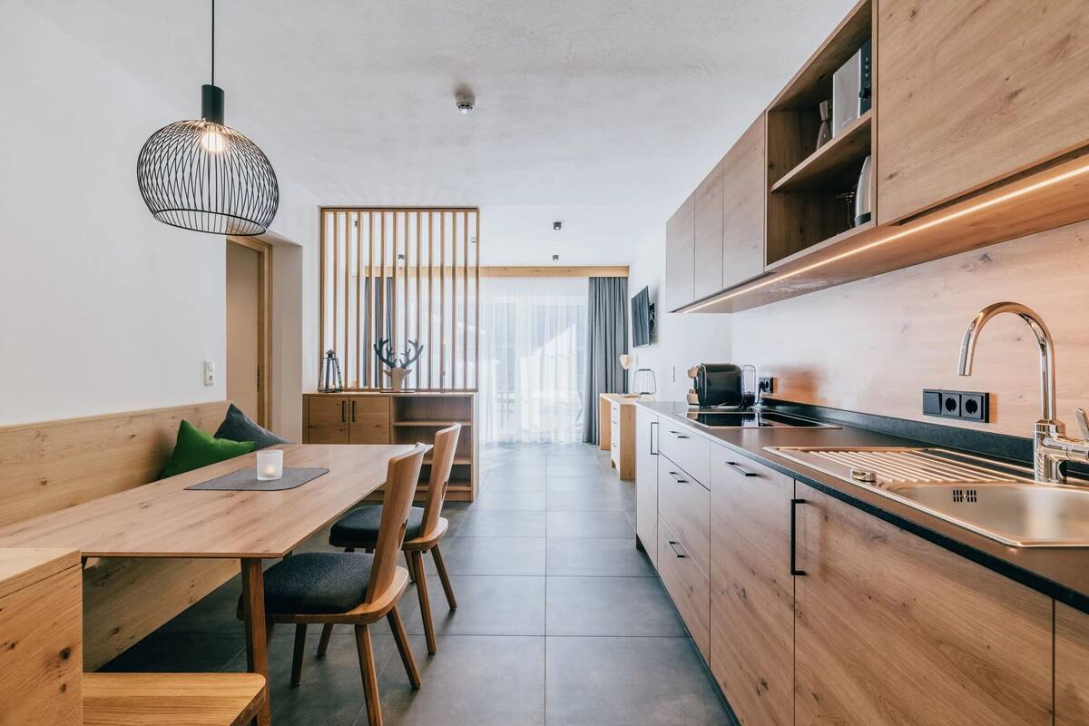 A modern kitchen with wooden cabinets, a black countertop, and a stainless steel sink.