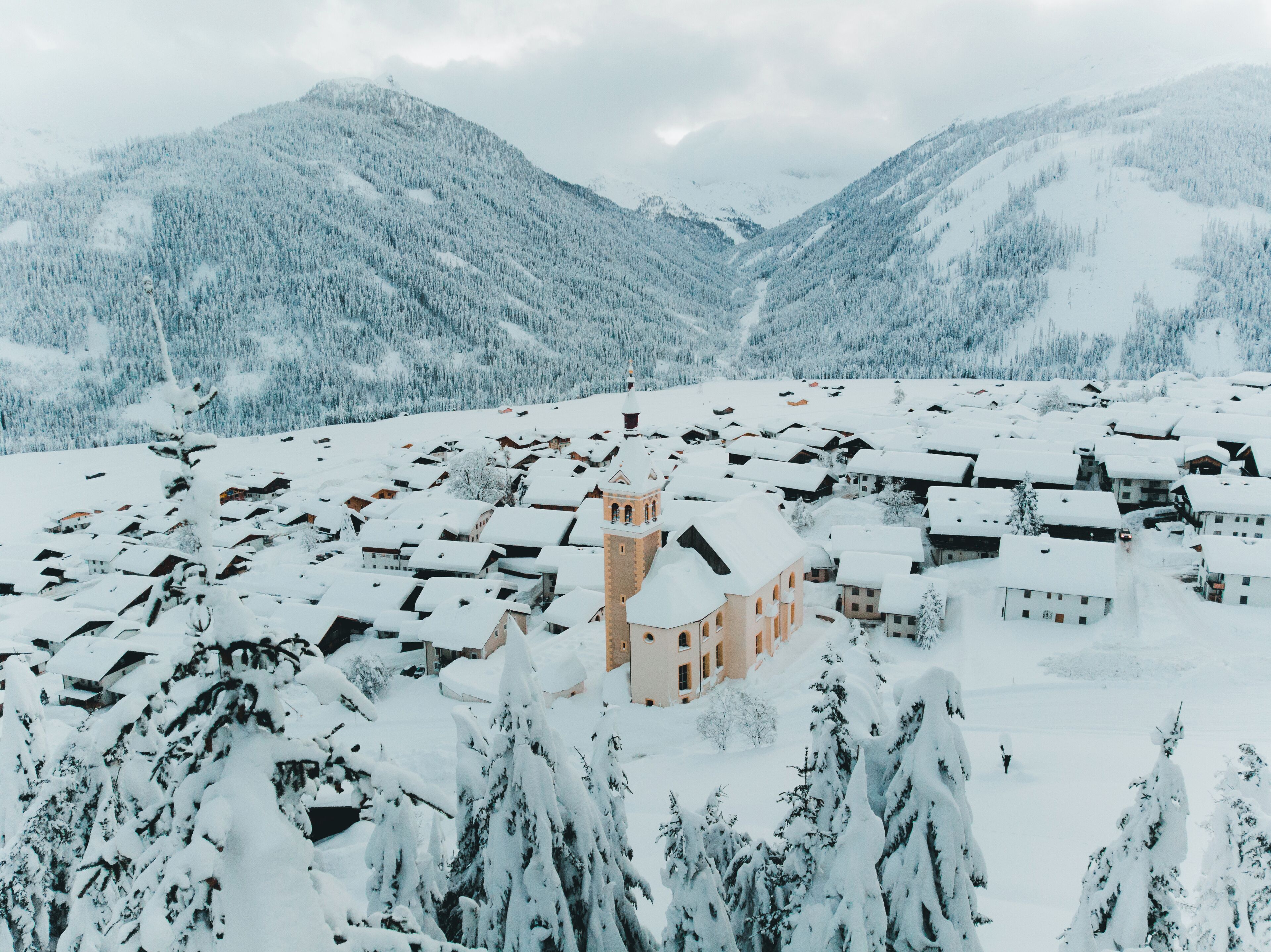 Un pueblo cubierto de nieve con edificios tradicionales y una destacada torre de iglesia.