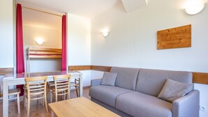 Ein Zimmer mit einem Etagenbett, einer Schlafcouch, einem Tisch und Stühlen.