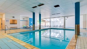 An indoor swimming pool with clear blue water, tiled flooring, and lounge chairs along the sides. - Près des Pistes! Studio Charmant | Accès Sauna (La Féclaz)