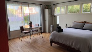 Une chambre à coucher avec un lit, une table et des chaises, un radiateur et une plante en pot.