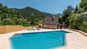 Piscina con vista a una casa y montañas.