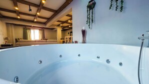 A large, white, freestanding hot tub in a room with wooden beams on the ceiling. - Villa Freya (Sapanca)