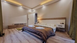 A modern bedroom with a large bed, bedside tables, a nightstand, and a wooden bench. - Villa Freya (Sapanca)