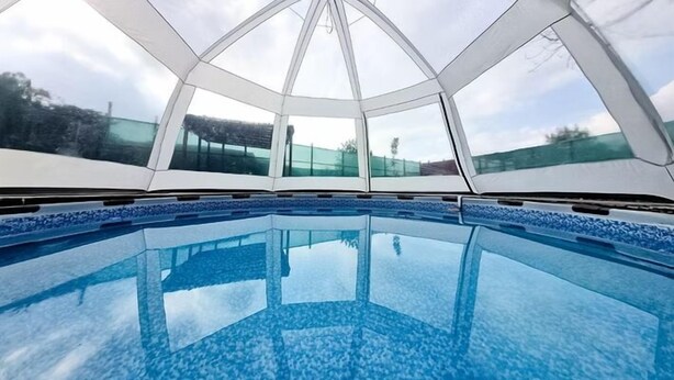 A modern indoor swimming pool with a geometric glass ceiling and clear blue water. - Villa Freya (Sapanca)