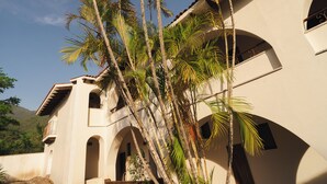 A building with multiple balconies, arched windows, and palm trees. - Hotel Hacienda Concá (Concá)