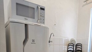 Une cuisine de taille réduite, avec un réfrigérateur blanc, un four à micro-ondes et un évier.