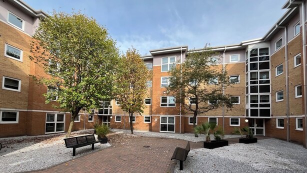 A courtyard with brick pathways, benches, and trees. - Student Only The Railyard (Liverpool)