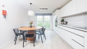 A modern kitchen with white cabinets, a wooden dining table, and black chairs. - Student Only The Railyard (Liverpool)