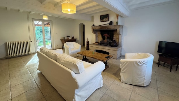 Una sala de estar con sofá, sillón y chimenea.