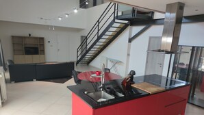 Cozinha moderna com ilha vermelha, bancadas pretas e exaustor de aço inoxidável.