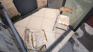Uma pequena área externa com assentos para dois e uma porta.