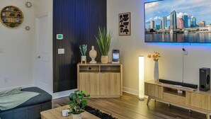 Ein modernes Wohnzimmer mit Blick auf die Stadt, einer Holzkabine mit Dekoration, einem Fernseher und einer gemütlichen Sitzecke.