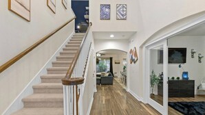 Ein modernes Interieur mit einer Holztreppe, einem Wohnbereich mit einer Couch und einem Essbereich.